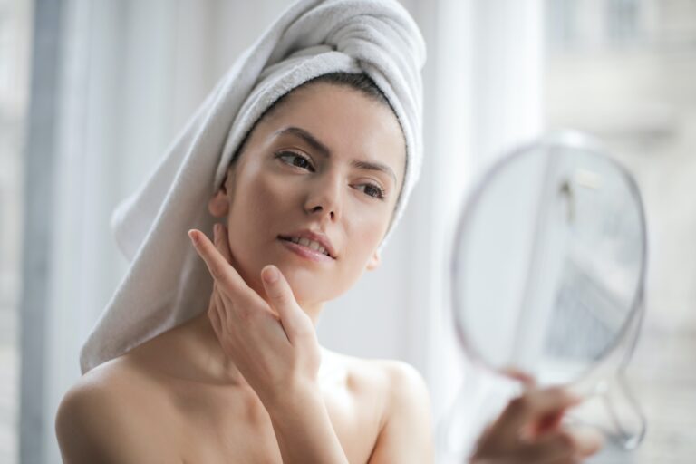 woman looking in mirror cleaning her face